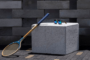 bancas de concreto para jardin tipo cubo con una raqueta recargada y encima de la banca unos lentes de sol